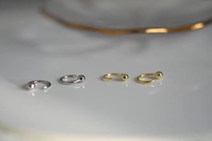 Vista detallada de pendientes minimalistas en forma de C con acabados en plata y oro