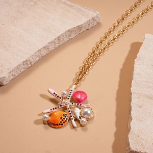 Detail of starfish and shell necklace with pearls and rhinestones on a sandy beach setting