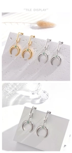 Macro detail of crescent horn earrings in gold and silver finish with green gemstone