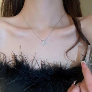 Detail shot of a silver four-pointed star pendant necklace with sparkling zircon on a model