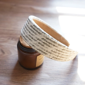 Detail view of woven raffia headband in beige and grey on a vintage glass bottle