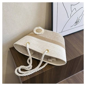 Detail of beige woven tote bag featuring white daisy decor and thick cotton rope handles
