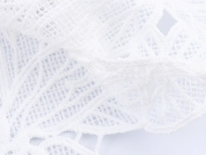 Close-up of elegant white lace material with intricate mesh patterns and woven textures