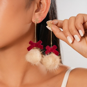 Vintage snowflake earrings with red velvet bows and beige pompons on a model
