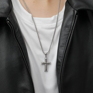 Polished stainless steel cross pendant necklace on a model wearing a leather jacket