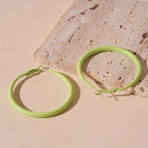 Close-up of mint green round hoop earrings placed on a natural stone display base
