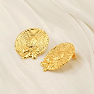 Elegant gold bow straw hat stud earrings in stainless steel on white silk fabric