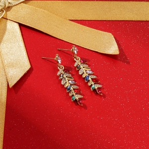 Detail view of colorful marquise crystal leaf earrings on a festive red background