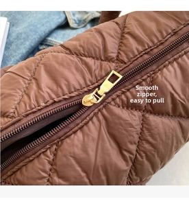 Detail of coffee brown quilted puffer bag featuring a smooth gold zipper and puffy texture