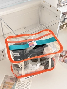 Close-up of a clear PVC waterproof makeup bag with orange trim and blue handles