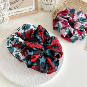 Three floral scrunchies with red rose prints in black, white, and pink fabrics
