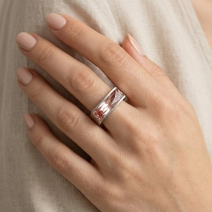 Macro detail of a square pink gemstone set in a minimalist stainless steel band
