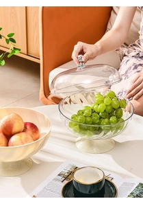 Close-up of elegant clear striped fruit bowl with lid and gold handle on beige table