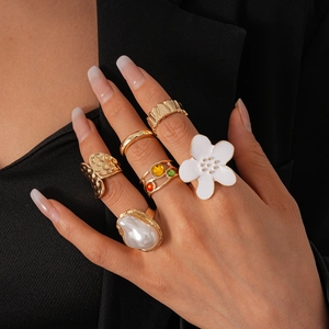 Gros plan d'un lot de 6 bagues dorées avec perles, fleurs et motifs en métal texturé