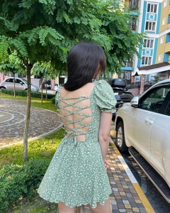 Détail d'une mini robe fleurie verte avec un design dos nu à nouer et manches bouffantes