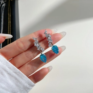 Macro detail of pear-shaped blue heart earrings with marquise-cut zircon in silver setting