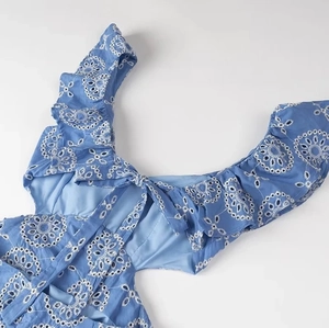 Detail of blue eyelet embroidery with intricate cut-outs and romantic ruffle accents