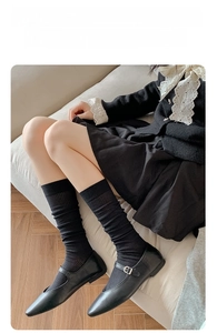 Detail of black ribbed calf socks with sheer texture worn with Mary Jane leather shoes