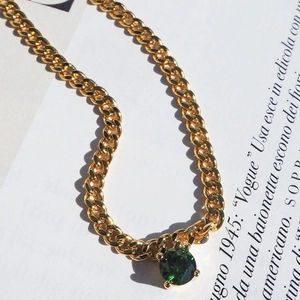 Macro detail of 18k gold plated Cuban chain necklace with green zircon gemstone pendant