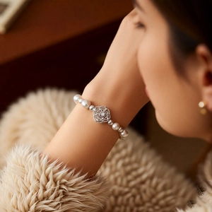 Detailed view of pearl bracelet featuring a silver camellia flower charm with zircon