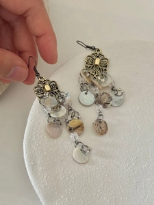 Detail of vintage long tassel earrings featuring shell discs and gold hollow floral charms