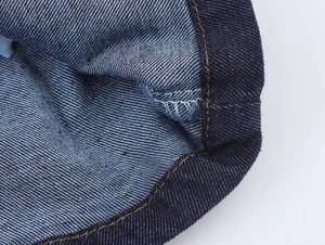 Dettaglio del tessuto denim blu scuro con cuciture arancioni e trama del materiale