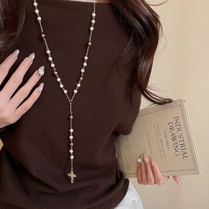 Detail of vintage cross pearl necklace on model with bronze and white beads