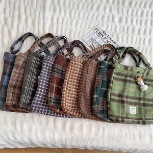 Flat lay of colorful wool plaid tote bags with textured patterns and long shoulder straps