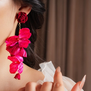 Gros plan d'un mannequin portant des boucles d'oreilles fleurs en tissu rouge vif