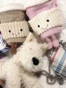 Group shot of cartoon coffee cup plush toys and checkered bags on soft white fur carpet