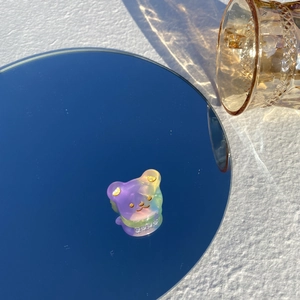 Gros plan sur une pince à cheveux ours en acétate avec dégradé violet et vert sur miroir