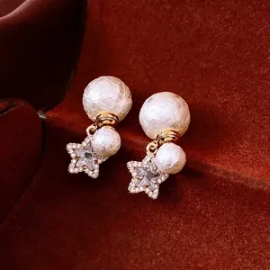 Elegant 18K gold plated star and pearl earrings with crystal accents on red velvet