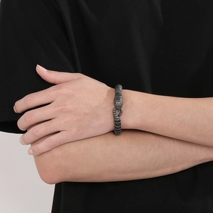 Dettaglio del bracciale in acciaio a scaglie di serpente nero lucido sul polso