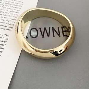 Gros plan d'un bracelet doré irrégulier poli sur un fond minimaliste chic