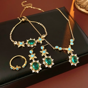 Détail d'une parure vintage dorée avec émeraudes ovales et zircons turquoise