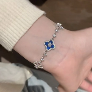 Detailed view of a silver floral bracelet with blue inlay and zircon accents on a wrist