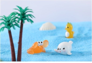 Macro shot of resin crab and seal figurines on blue sand for miniature ocean scenes