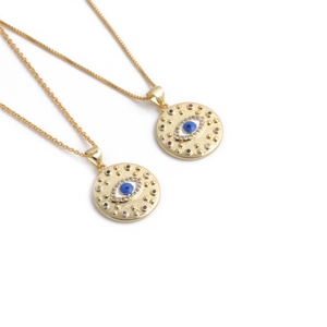 Détail de deux colliers cœur en plaqué or avec zircons colorés au motif œil grec