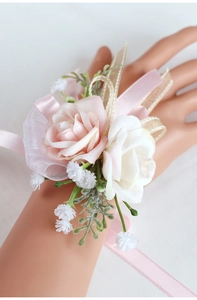 Dettaglio di un corsage da polso con rose artificiali rosa e bianche per il matrimonio