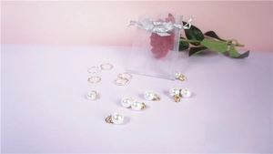 Detail of white pearl pendants with gold hoops and purple organza jewelry pouch