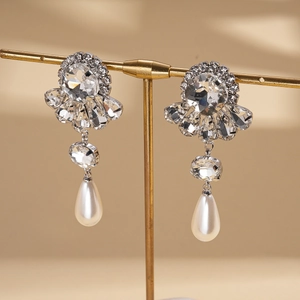 Macro shot of silver drop earrings with floral crystal stud and teardrop pearl detail