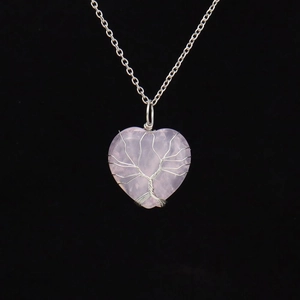 Detailed view of silver wire-wrapped tree of life on a pink quartz heart pendant
