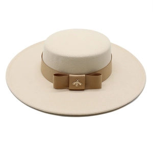 Flat lay of oatmeal wool felt flat top hat with wide brim and gold bee metal ornament