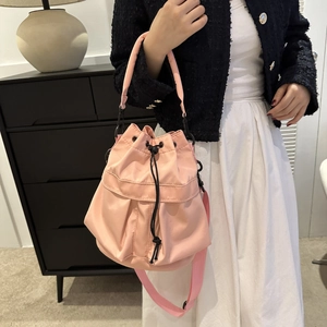 Détail d'un sac seau rose avec cordon de serrage noir porté par un mannequin en mode lifestyle