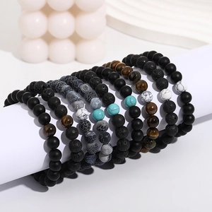 Stack of natural stone beaded bracelets including turquoise and lava rock on a white stand
