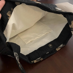 Macro view of inner canvas lining and magnetic snap button of the floral shoulder bag