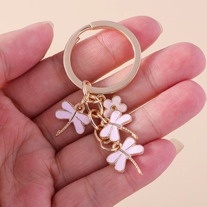 Close-up of golden keychain with three pink enamel dragonflies and a flower accessory