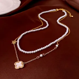 Double-layer pearl necklace with golden clover flower pendant on a dark satin background