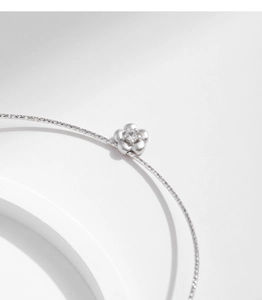 Detail of silver S925 floral pendant with sandblasted texture and central diamond