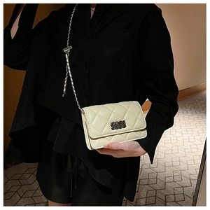 Close-up of quilted pattern and silver chain on a pale yellow crossbody square bag